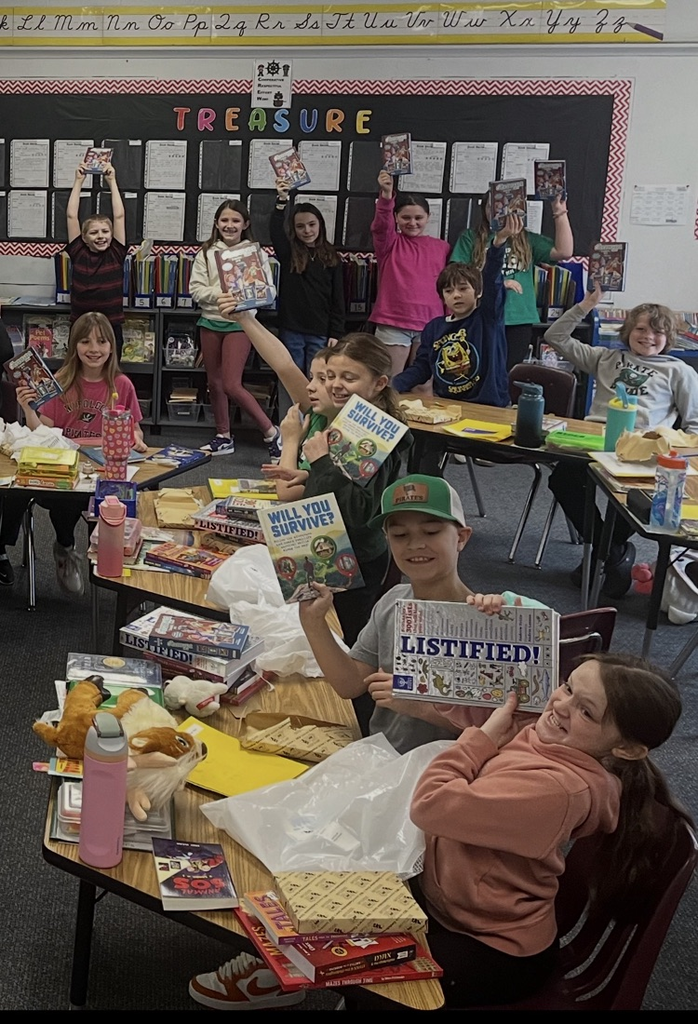 students in classroom holding up books