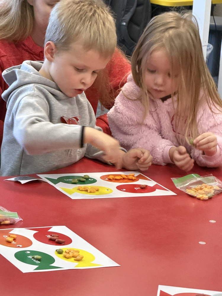 two kids sorting rainbow goldfish by color