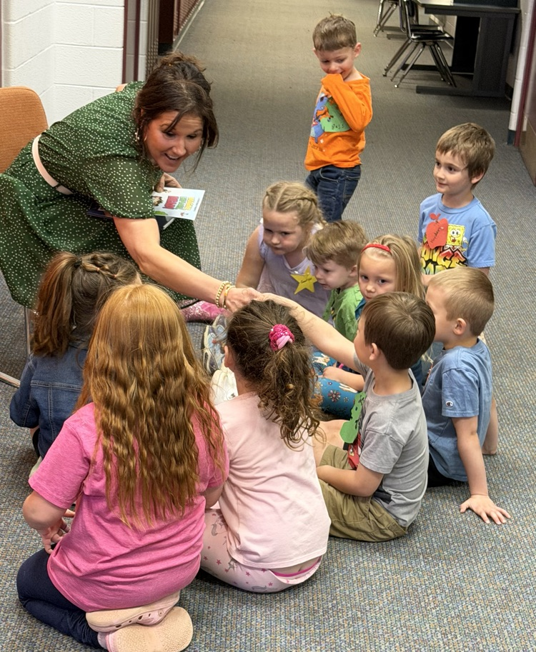 children sitting at the feet of a woman who is shaking their hands