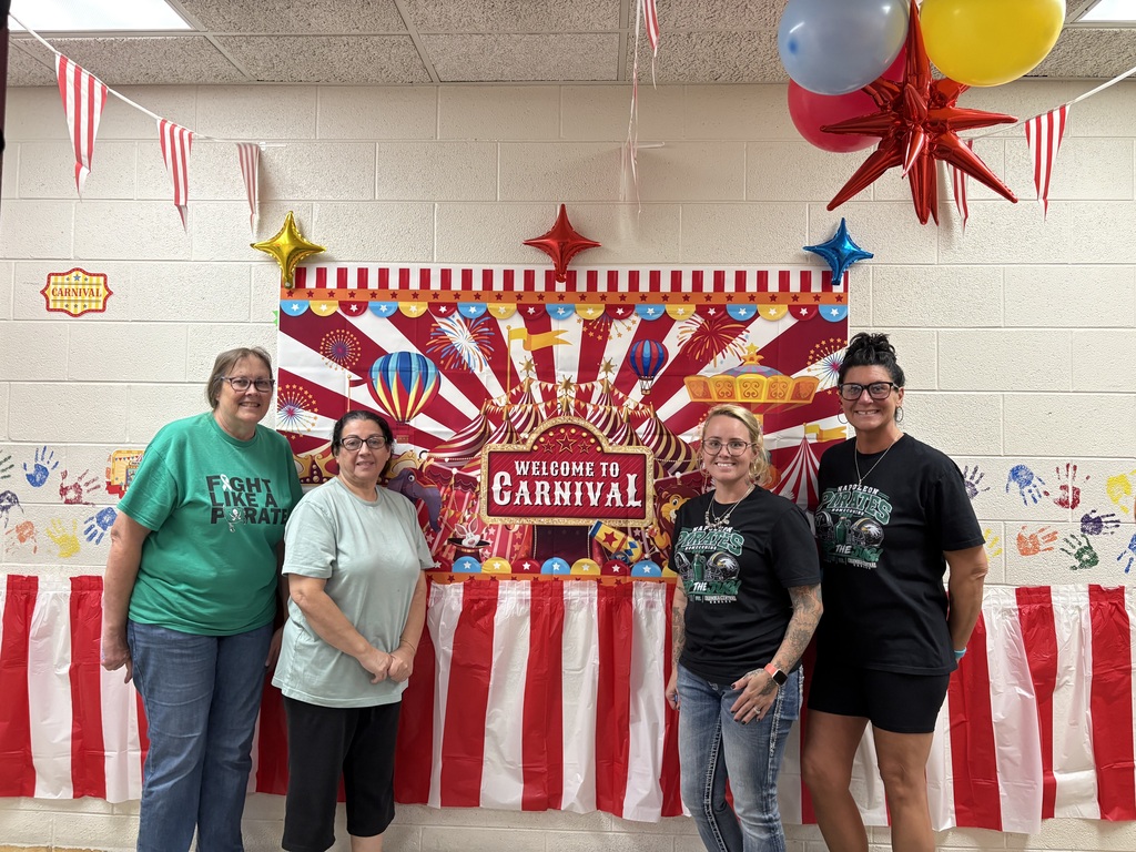 four ladies standing in front of carnival sign with balloons 