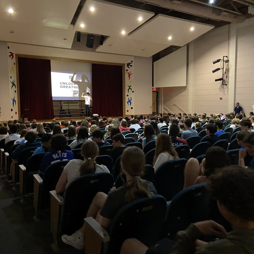 Middle school students sit in the auditorium and watch a presentation.