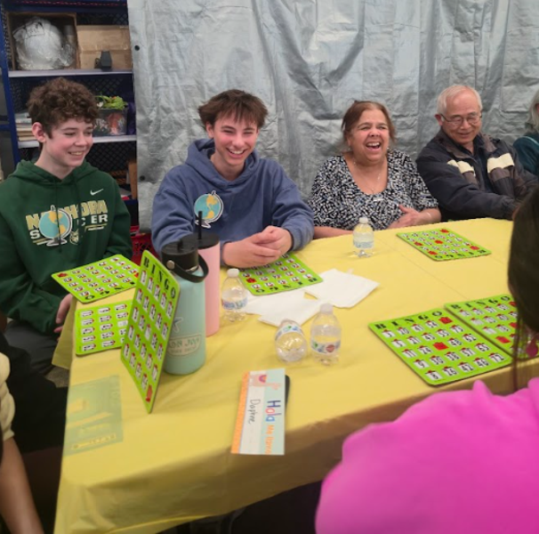 Students and community members sit at a table playing BINGO.