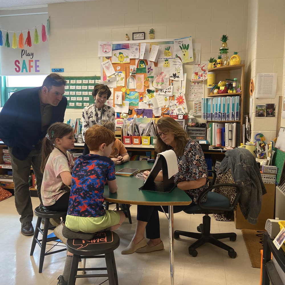 Senator Cronin and Assistant Superintendent Friend watch as MRE first grade students work with their teacher in a small group.