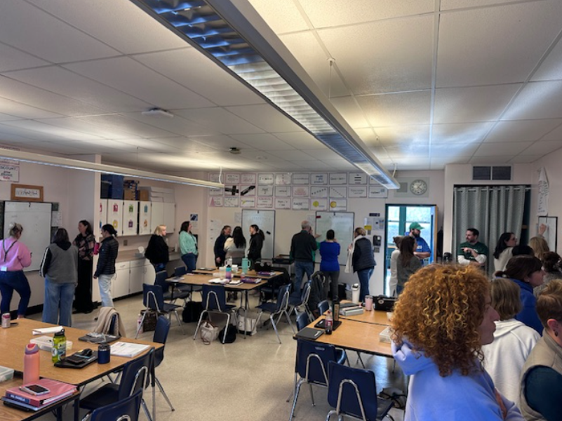 NRSD educators stands in small groups throughout a classroom.