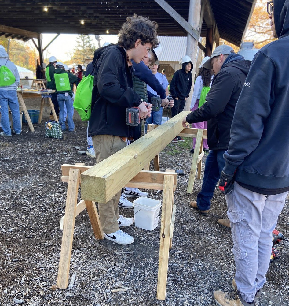 Student stands at a wood working table.