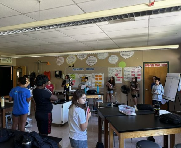 Middle school students gather in a large learning circle in their classroom.