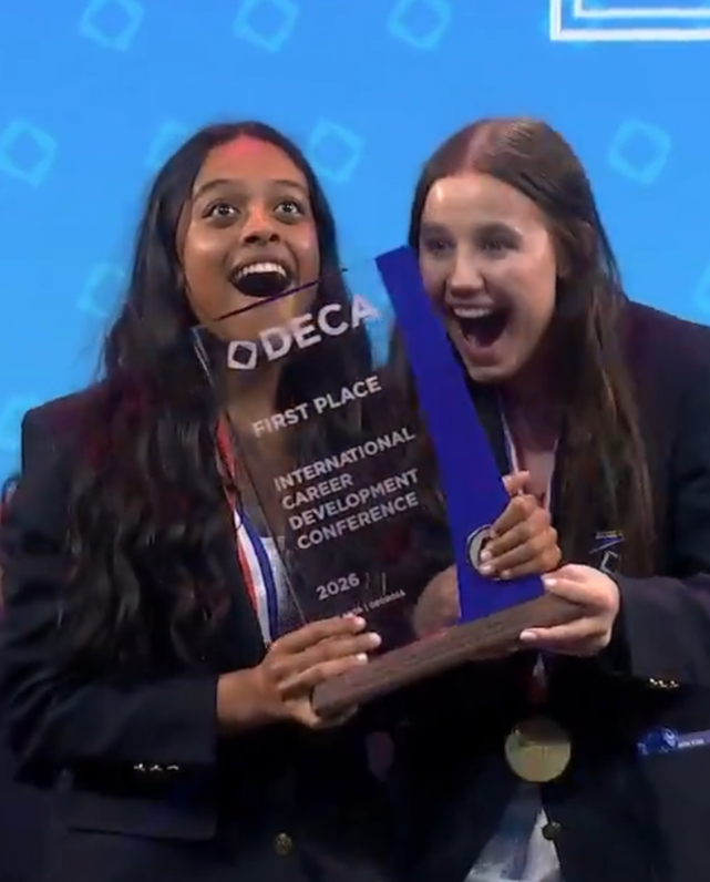 Two NRHS DECA students pose and smile with the first place trophy.