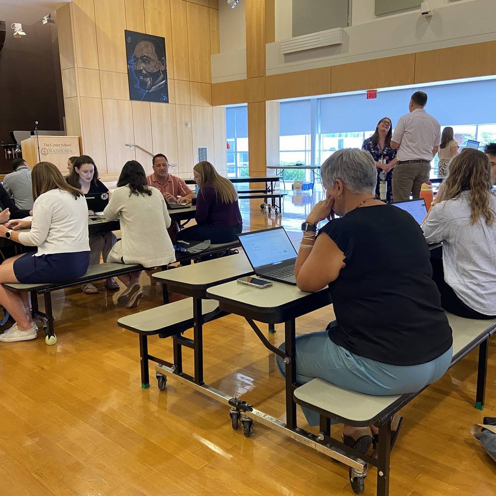 New NRSD educators sit together at cafeteria tables.