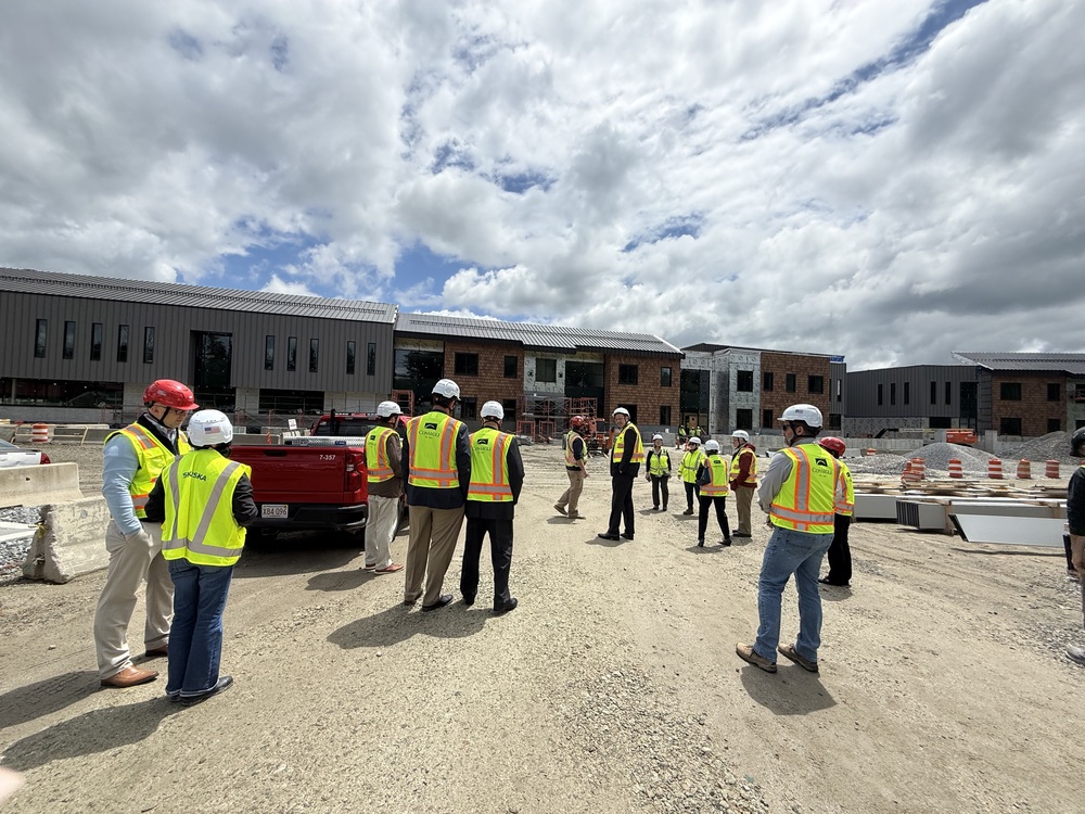 People dressed in safety gear walk towards the NRHS building site.