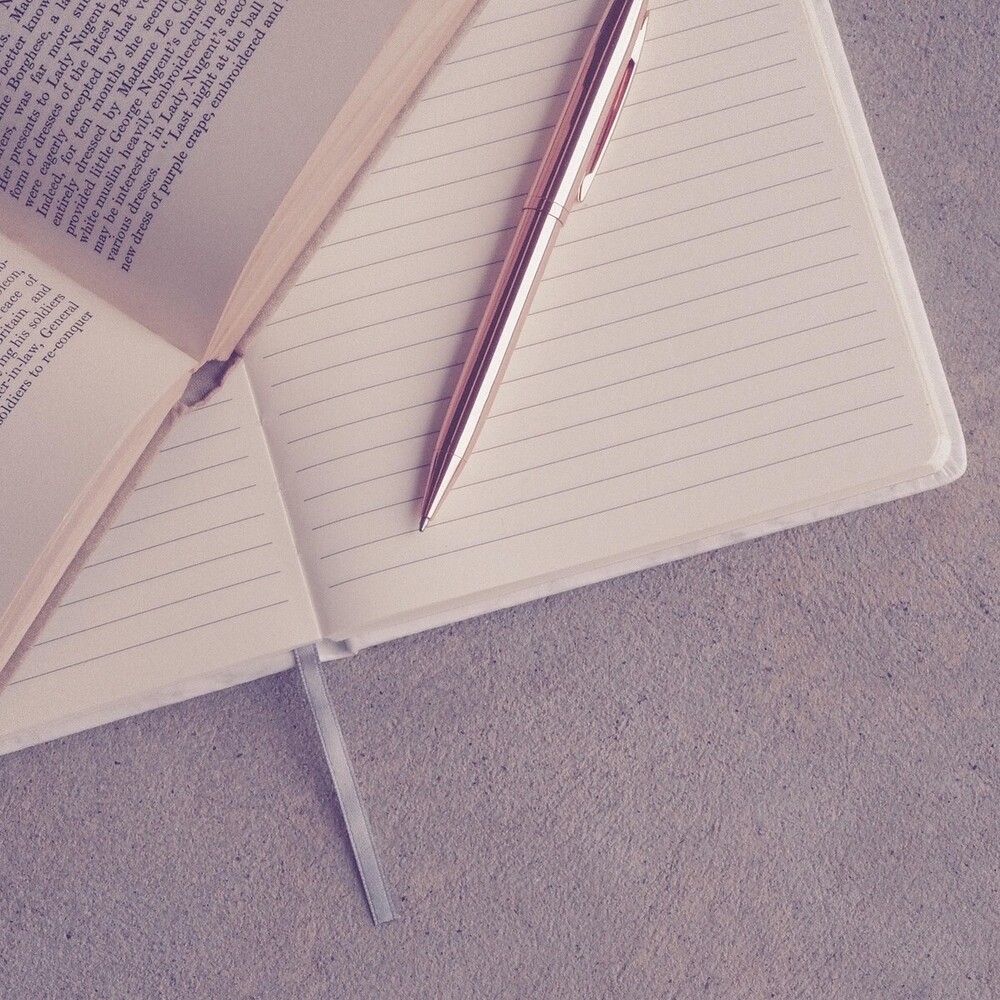 Notebook and book lay open on a table.