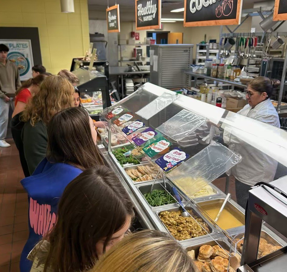 Students stand in a lunch line.