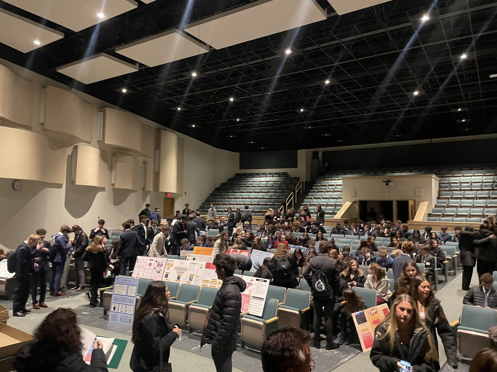 students waiting in the auditorium with large posters