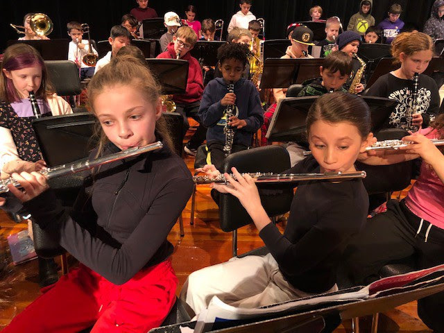 students sit in rows playing their instruments
