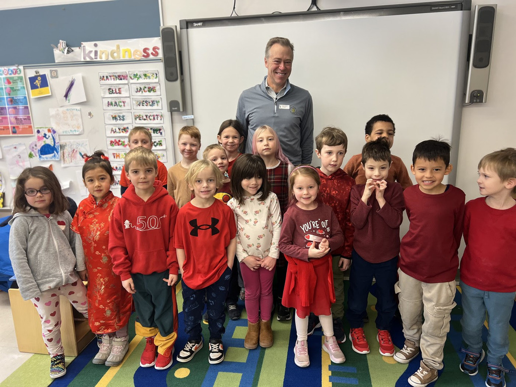 kindergarten students pose with a visitor in their classroom