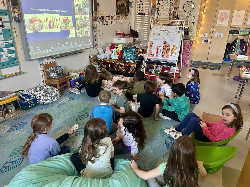 students sit on the ground while looking at a projector and talking