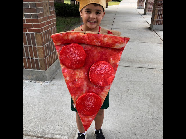 A student smiles dress as a giant piece of pepperoni pizza.