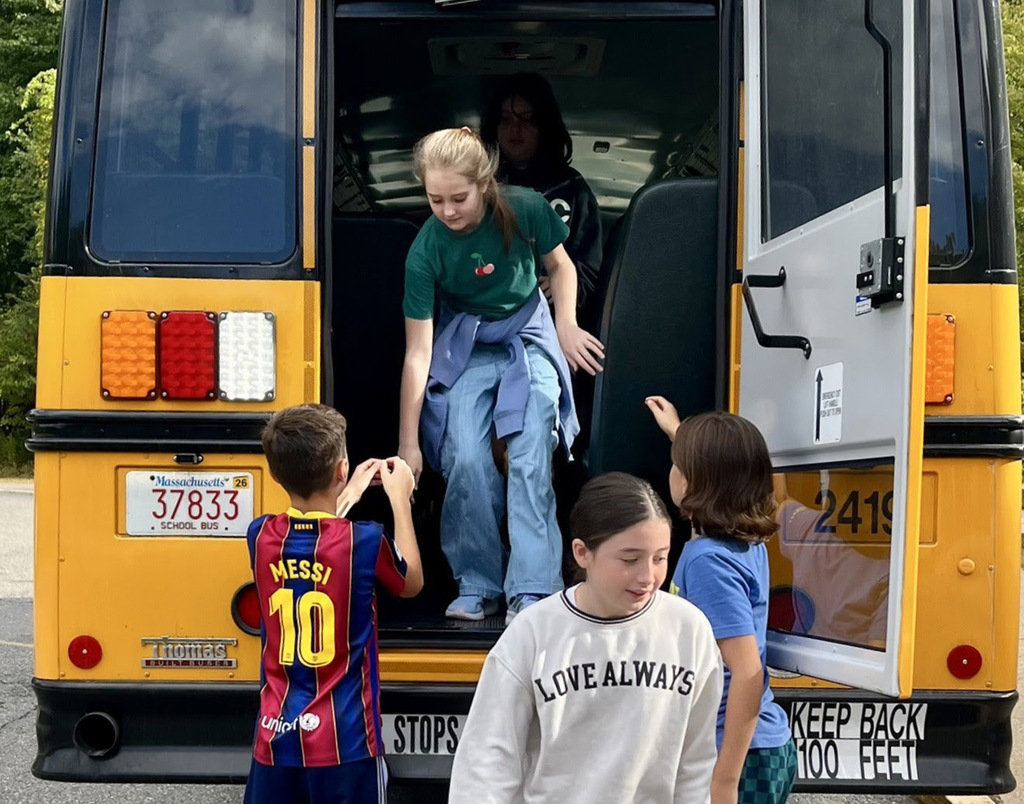 Students help each other out of a bus during an evacuation drill.