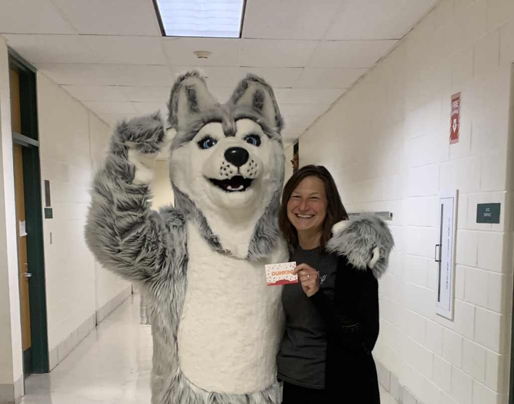 The MRE wolf mascot stands with an MRE teacher smiling.