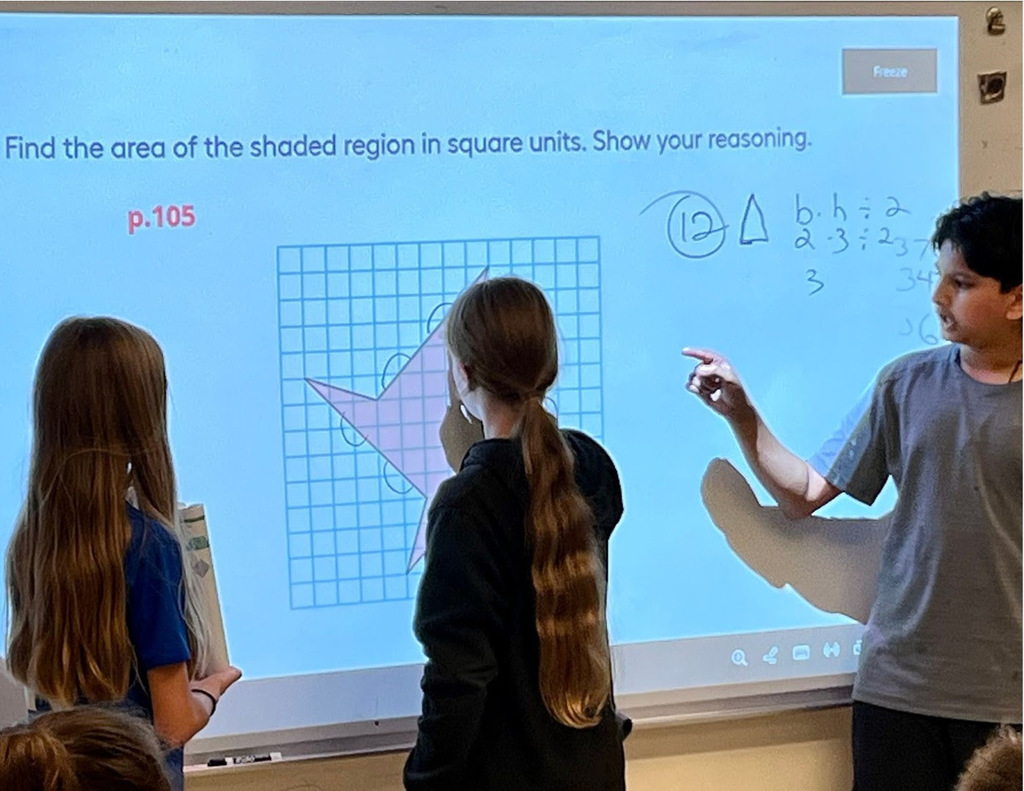 Three FSS sixth grade students stand in front of the whiteboard solving an area problem.