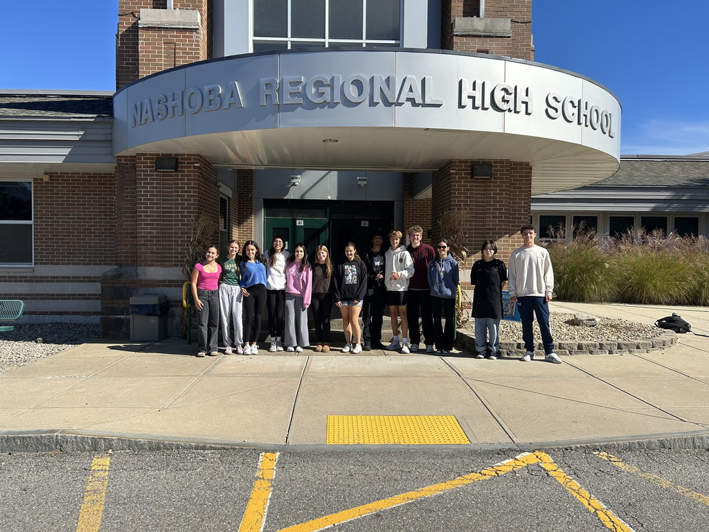 A group of thirteen NRHS students pose as a group in front of the NRHS entrance.