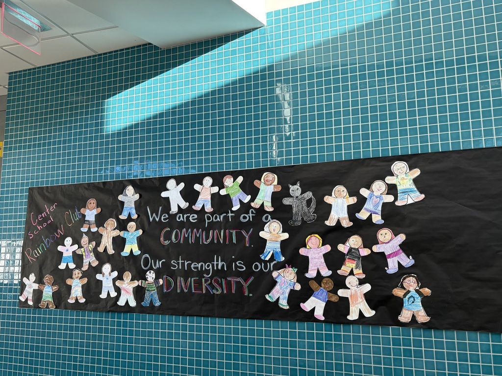 A banner hangs on the wall that says, "We are a part of a community. Our strength is our diversity."