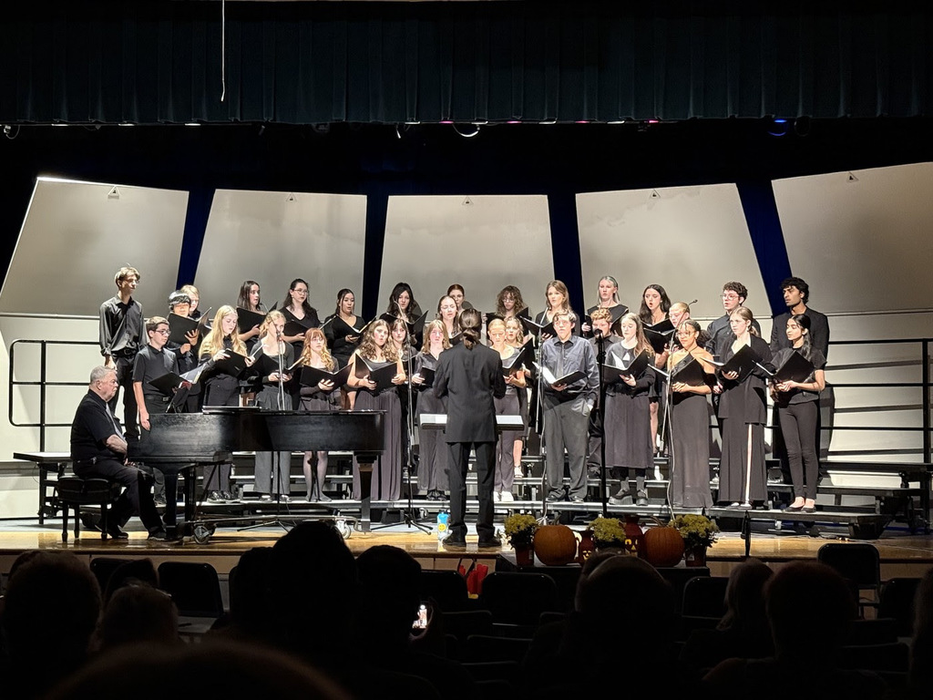 Members of the NRHS Choir perform on stage wearing all black.