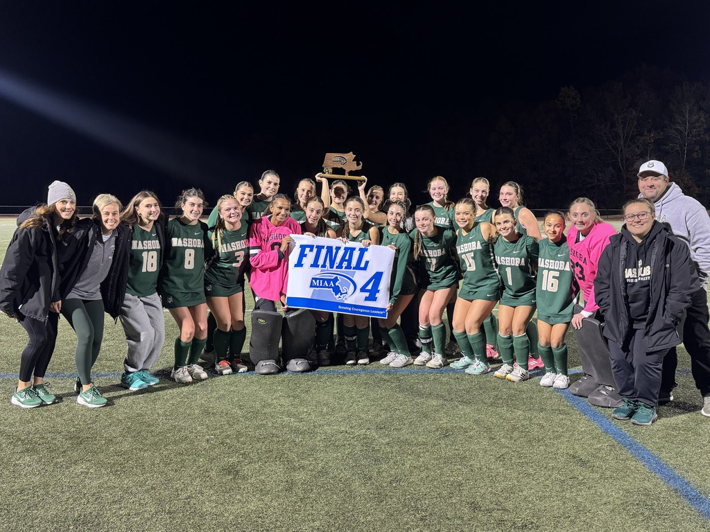 The NRHS Girls Field Hockey team poses on the turf after a win holding an MIAA Final 4 Banner.