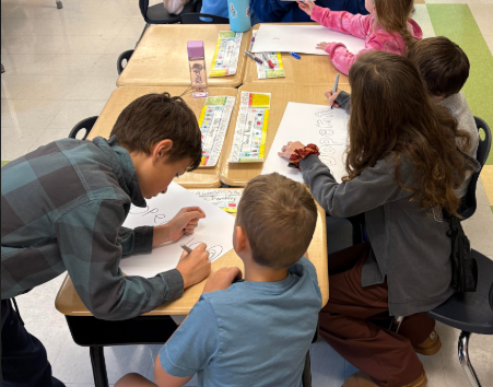 Center School first and fifth grade students work together to create posters about cooperation. 