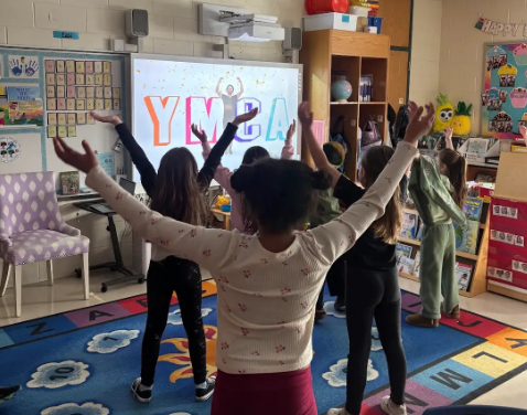 Elementary students do the YMCA inside their classroom.
