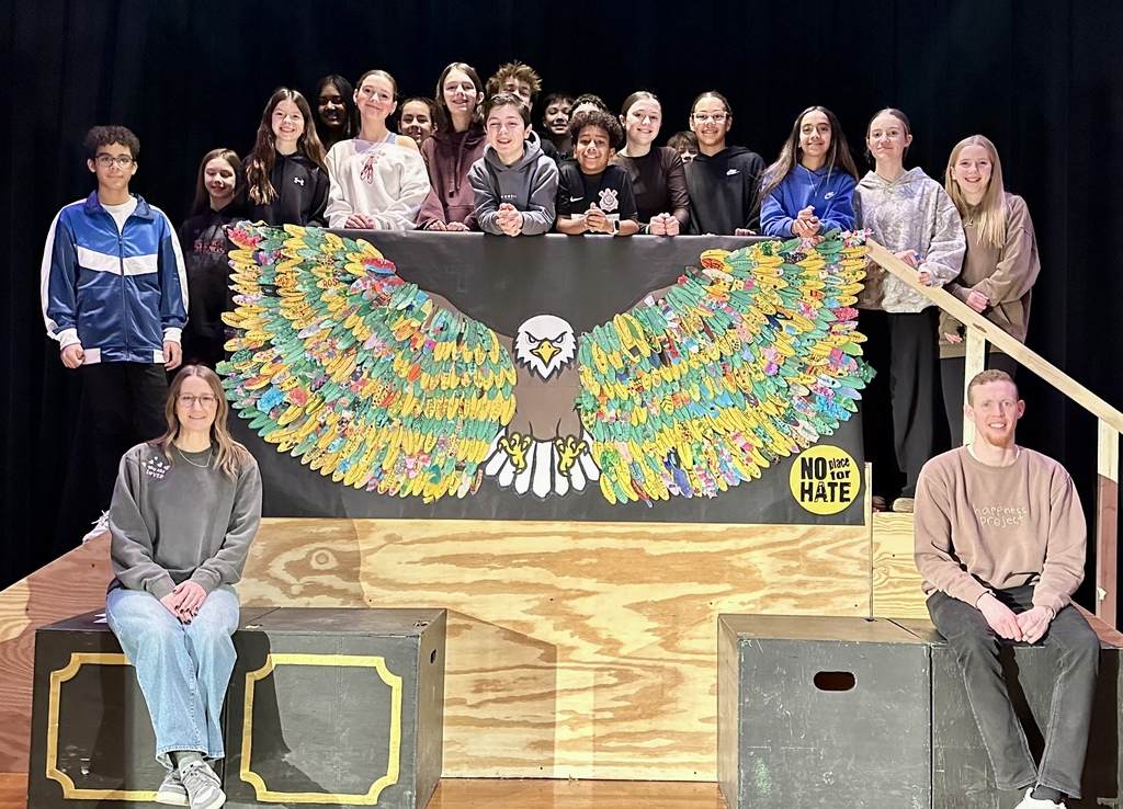 Students and counselors pose next to a large eagle made from paper  with it's wings spread.