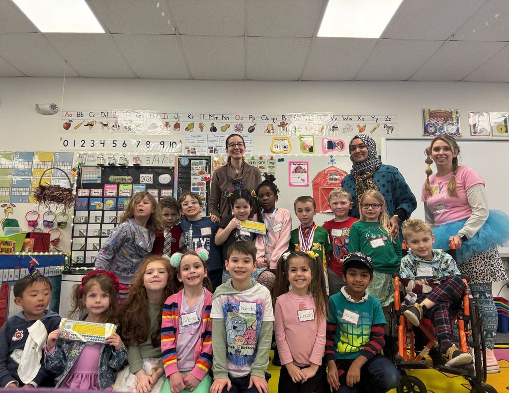 Elementary school students take a class photo with their teachers on wacky Wednesday.