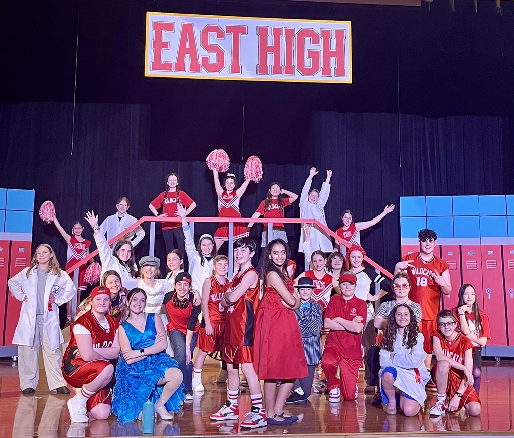 FSS Drama students post on a stage in their High School Musical Jr. costumes.
