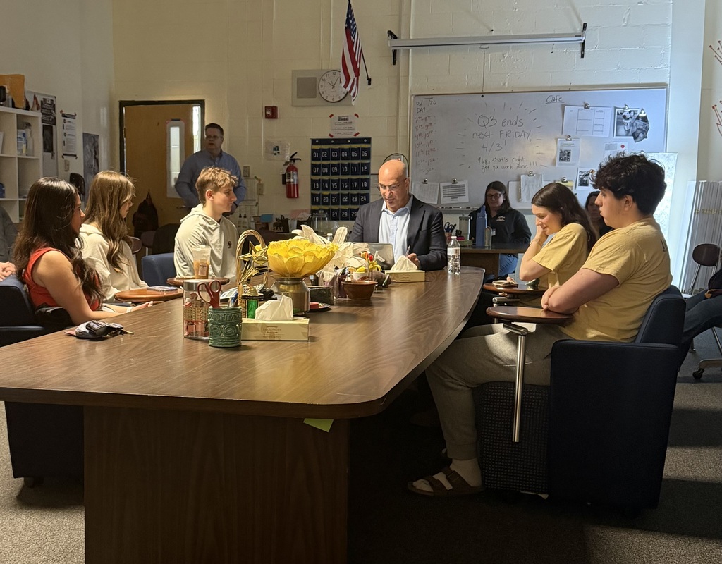 Students sit around a table with author Tony Frontier. Nashoba teachers and administrators watch from the back of the room.