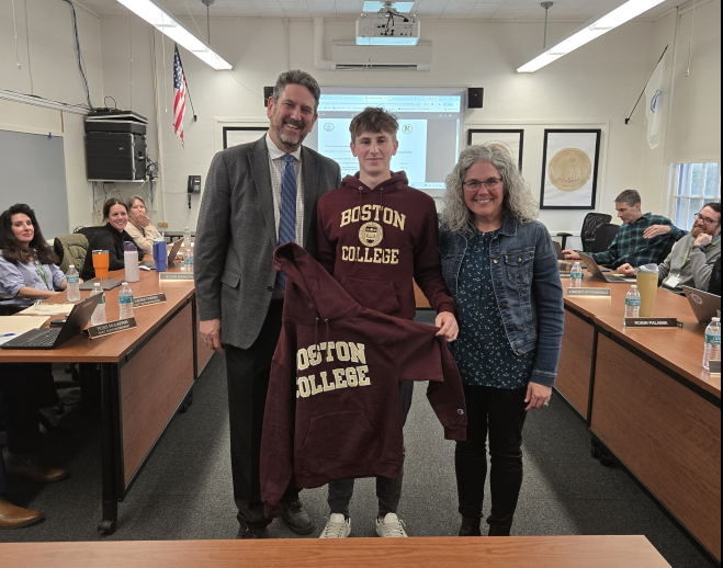 School Committee Student Representative, Ryan Mitrou, stands with a Boston College sweatshirt next to Superintendent Downing and School Committee Chair Vivirito.
