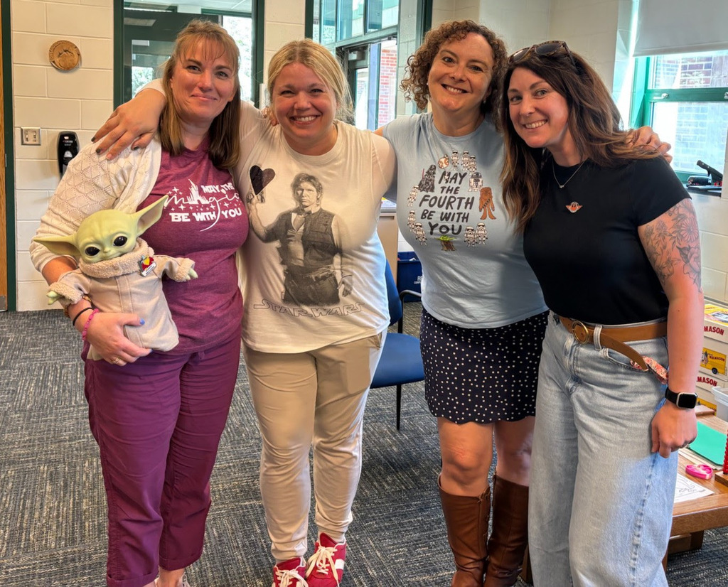 MRE staff members pose with Baby Yoda and with shirts that reference May the Fourth.