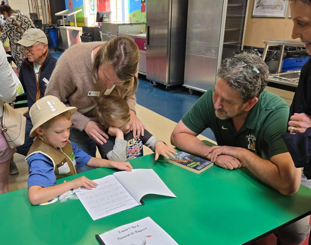 Superintendent Downing looks on with two students as they show off their report.