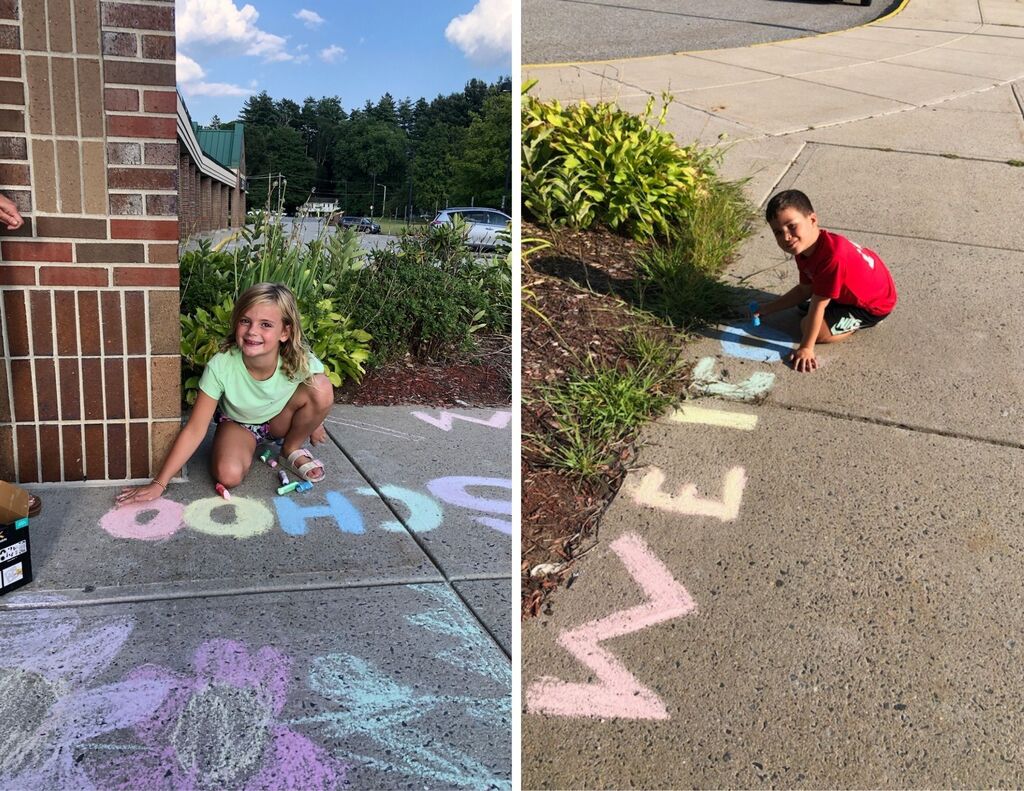 Two students use rainbow chalk to write welcome messages on entry sidewalks outside of MRE.