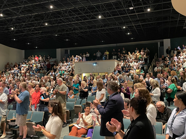 NRSD staff members stand in the NRSD auditorium clapping.