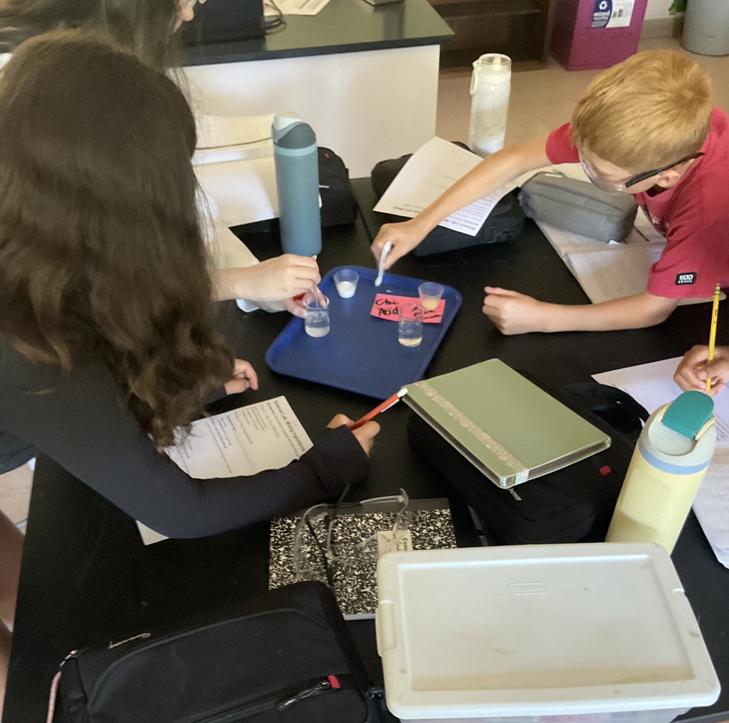 Middle school students conduct a science experiment and write in notebooks.