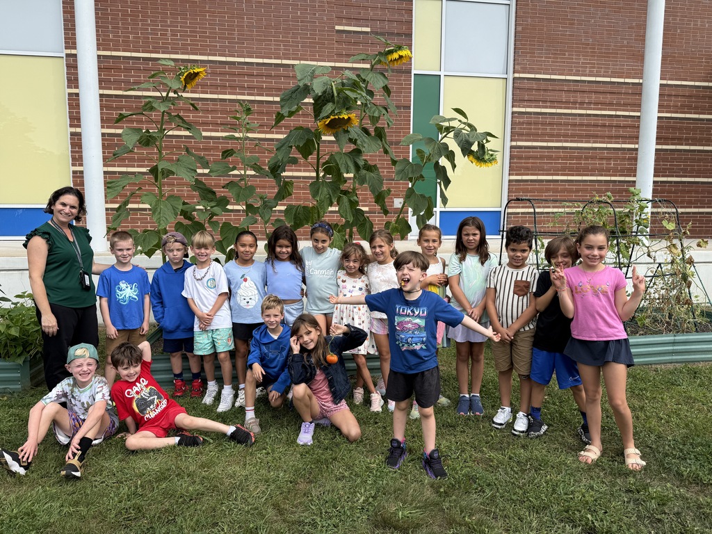 Students pose together as a class in front of the school garden.