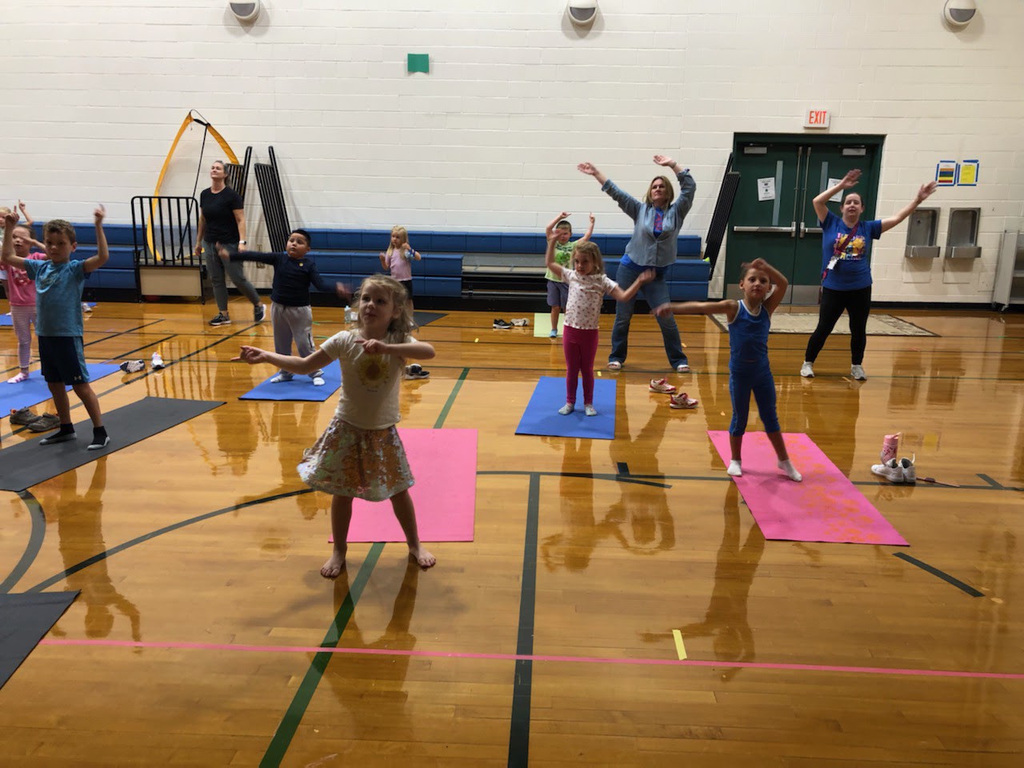 Kindergarten students at MRE do yoga in the gym with their teachers.