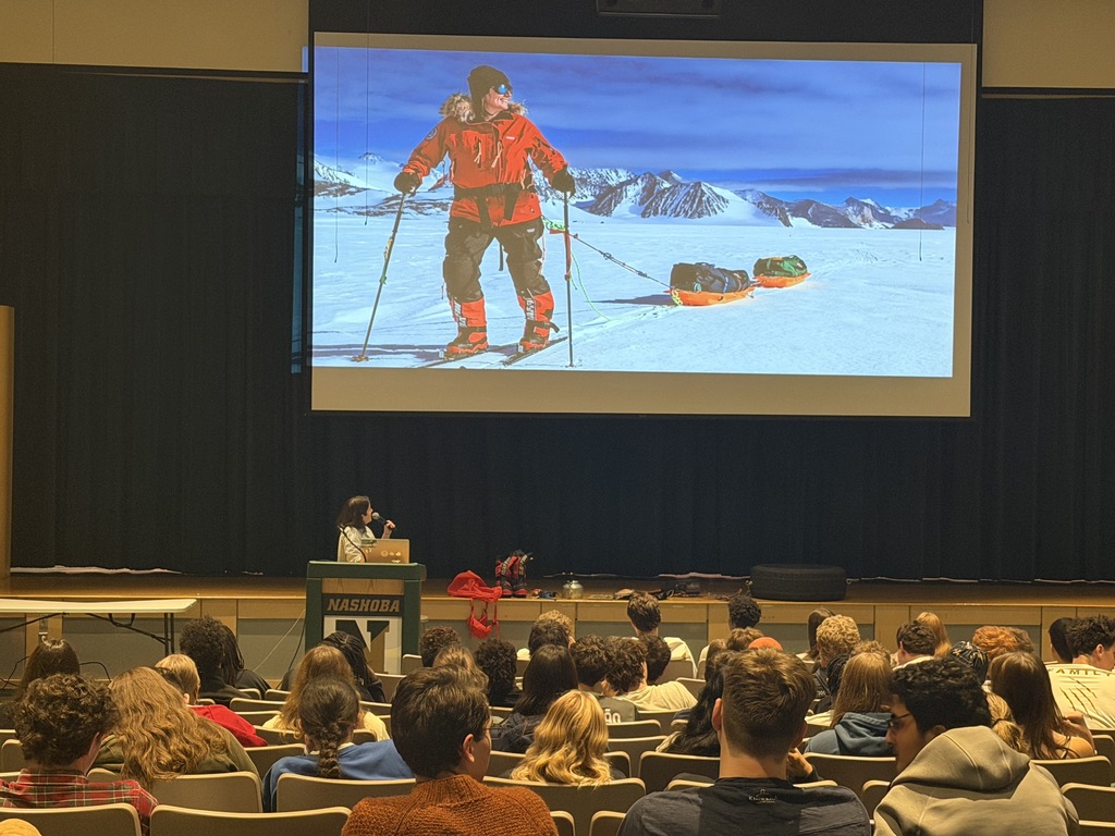 NRHS students listen to Class of 2008 graduate Monet Izabeth speak in the auditorium as a photo of her skiing across the South Pole is displayed on the screen.