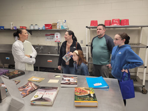 Chef-instructor C. Capraro talks about the Culinary Arts program with the Lavery family of Townsend – Mallory and Steven and daughters Daphne, a seventh-grader, and Gwen, a fifth-grader, during the annual Open House at Nashoba Valley Technical High School on November 2.