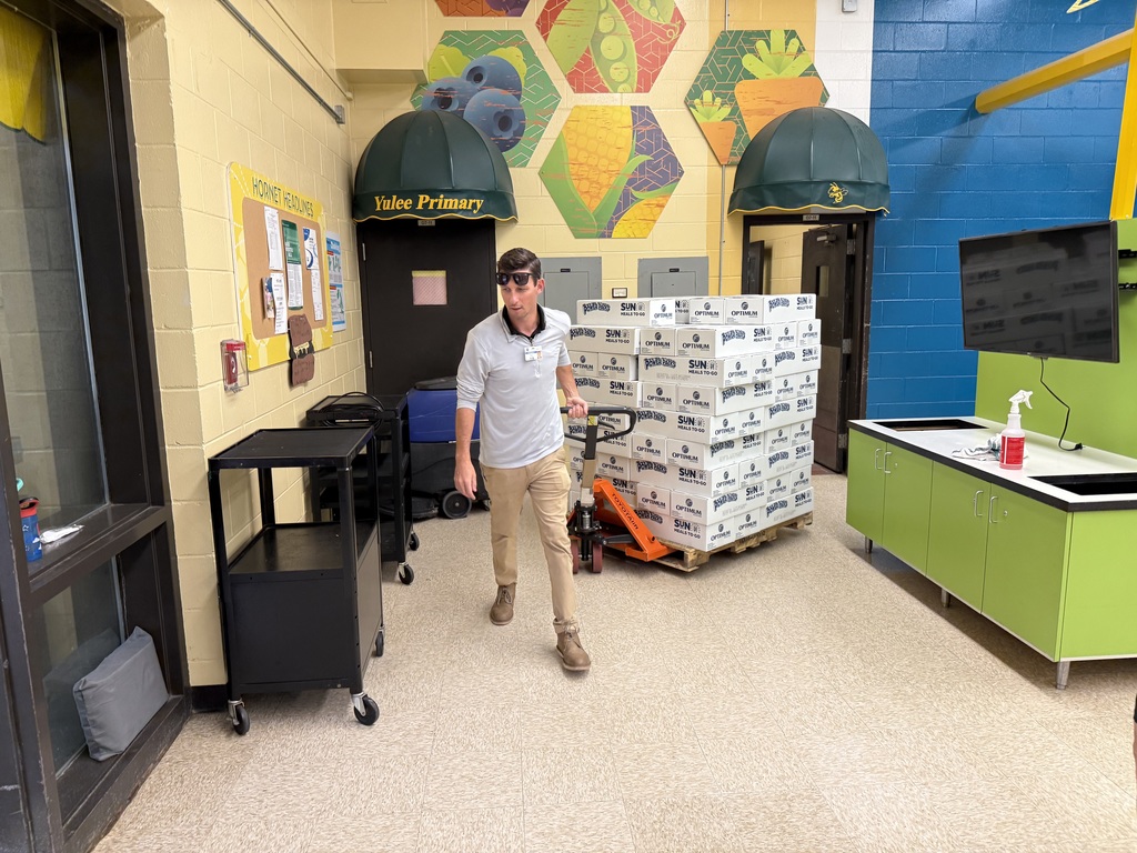 Food and Nutrition Services staff member moving a pallet of boxed meals inside Yulee Primary School’s cafeteria.