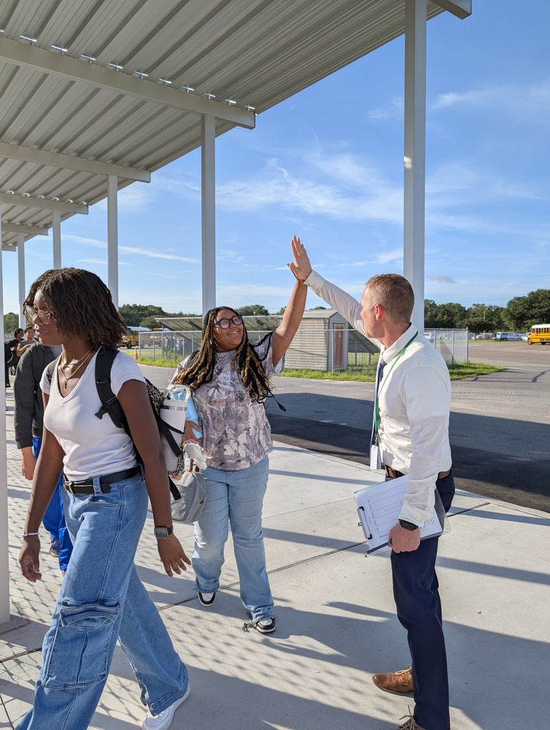 Dean high fiving students as they walk in the school