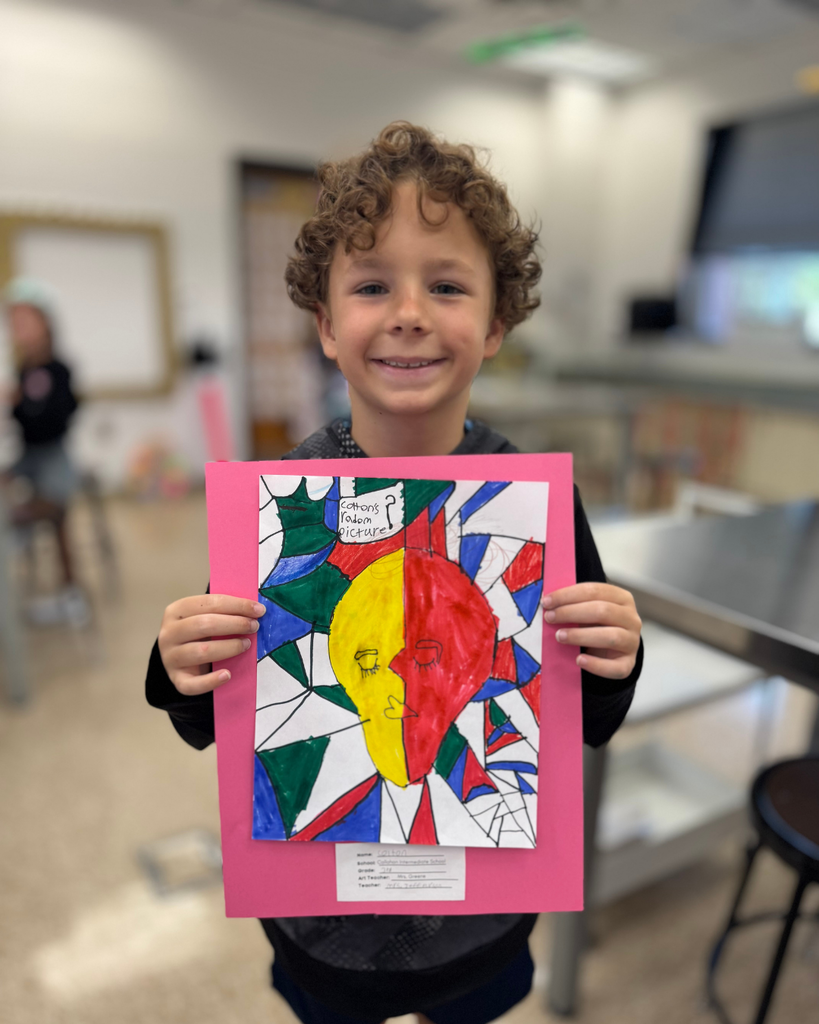 A student holds a Cubism self-portrait with a yellow and red face against a colorful geometric background, mounted on pink paper.