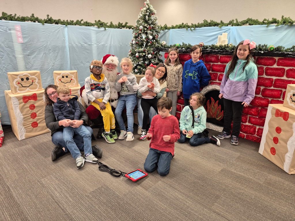 Students pose with Santa Claus in a decorated sensory-friendly space at Hilliard Elementary School with holiday decorations and a calm indoor setting.