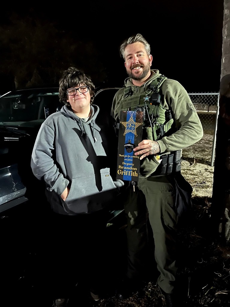 Deputy Griffith and student smiling with the plaque he made for the officer