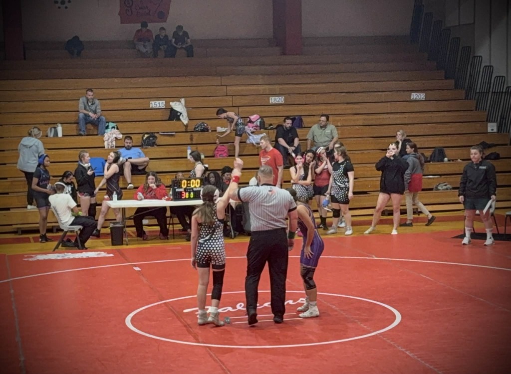 Wrestler has hand raised by referee after winning the match