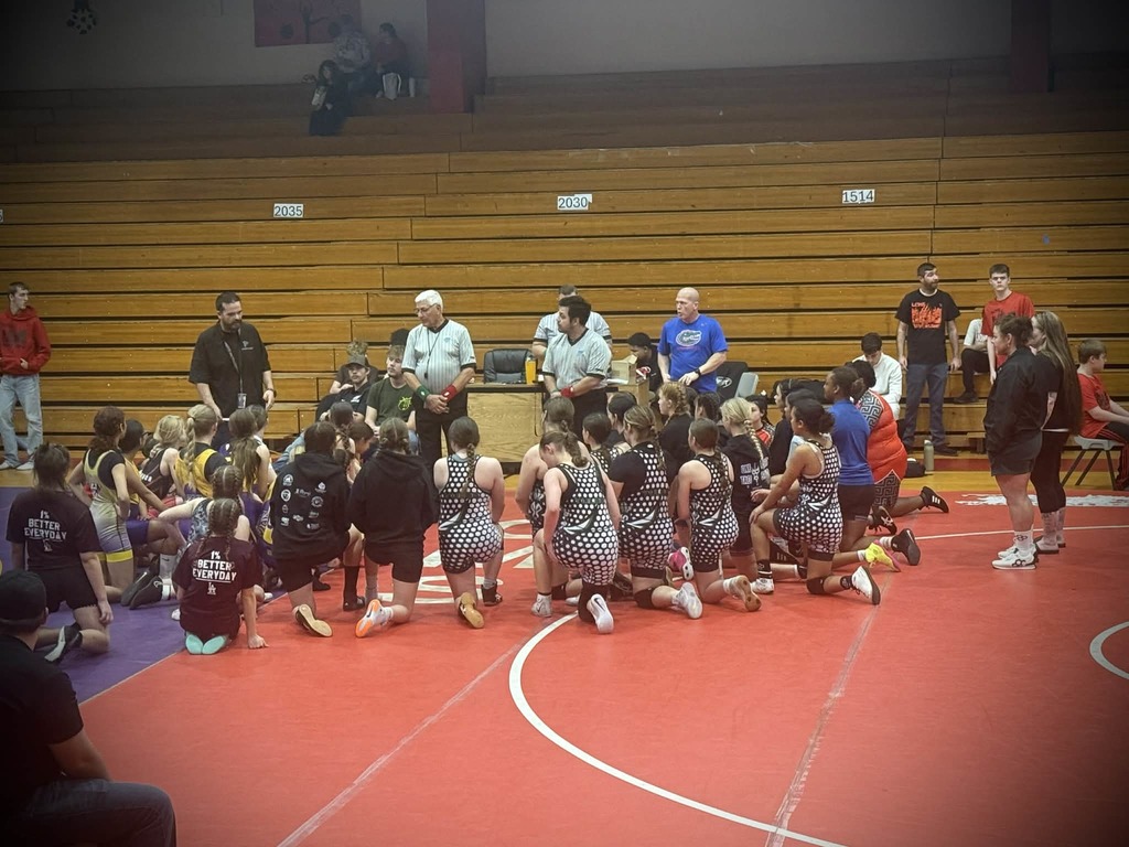 Wrestlers kneel as they listen to coaches